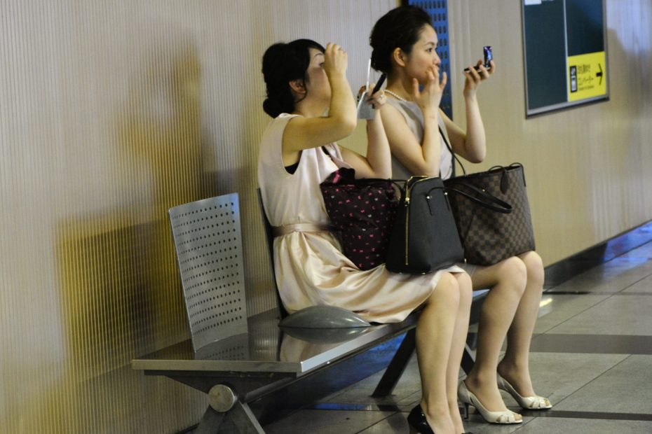 Dos mujeres asiaticas maquillandose en el metro