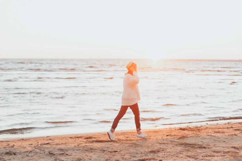photo of person walking on seashore